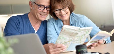 Ein älteres Paar beim Planen einer Reise mit einer Landkarte. (c) AdobeStock