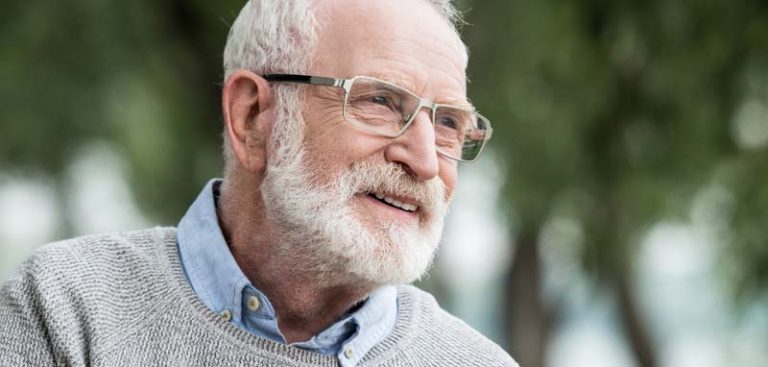 Das lachende Gesicht eines älteren Mannes mit Brille und weißem Vollbart. (c) AdobeStock