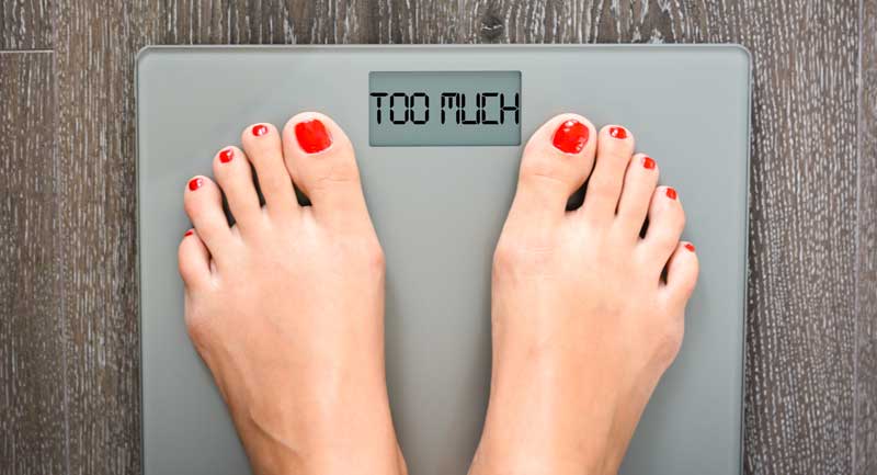 Die Füße einer Frau auf einer Körperwaage, die "Too Much" anzeigt, Stichwort gesunder Stoffwechsel.
(c) AdobeStock
