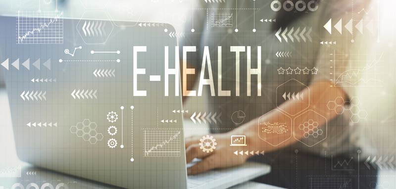 Die Arme einer Frau an einem Laptop, darüber e-Health und digitale Zeichen. (c) AdobeStock