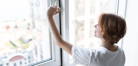 Eine Frau, die ein Fenster öffnet. (c) AdobeStock