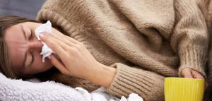 Doppelinfektion Covid und Influenza vermeiden, Schutz erhöhen Eine kranke Frau, die sich die Nase putzt. (c) AdobeStock