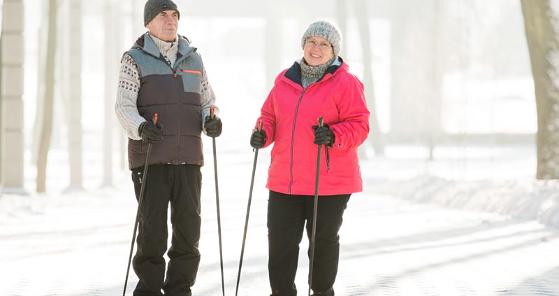 Ein älteres Paar beim Nordic Walken in einer sonnigen Winterlandschaft.
(c) AdobeStock