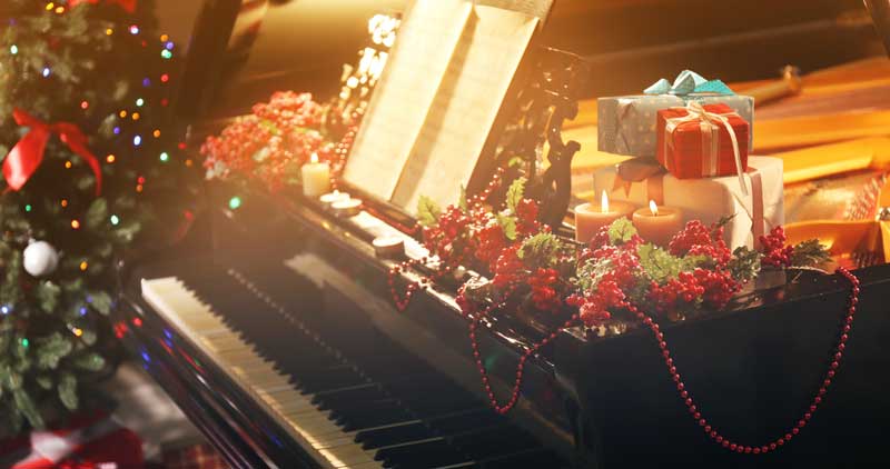 Ein Klavier, auf dem Weihnachtsdekoration und Geschenke liegen.
(c) AdobeStock