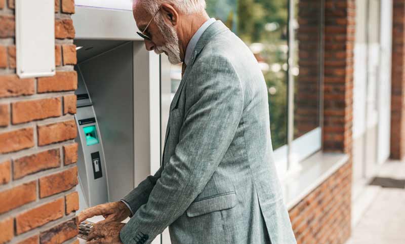 Ein älterer Mann hebt bei einem Bankomaten Geld ab, Stichwort Diskriminierungsschutz.
(c) AdobeStock