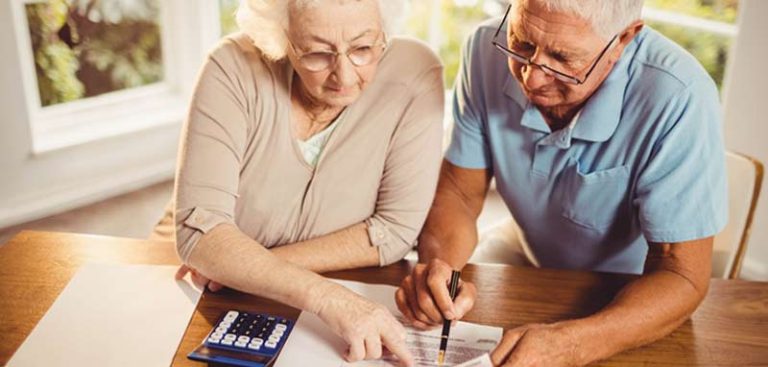 Ein altes Ehepaar an einem Tisch Finanzangelegenheiten besprechend. (c) AdobeStock