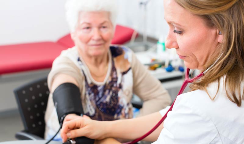 Eine ältere Frau bei einer Ärztin, die Blutdruck misst, Stichwort Krebs Früherkennung.
(c) AdobeStock