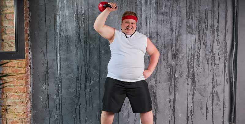 Ein übergewichtiger Mann beim Stemmen eines Gewichtes.
(c) AdobeStock