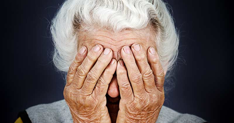 Eine alte Frau, die sich mit ihren Händen ihr Gesicht verdeckt, Stichwort Depressionen.
(c) AdobeStock