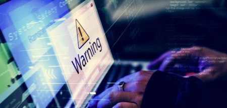 Die Hände eines Hackers auf einer Laptoptastatur, auf dem Bildschirm steht groß "Warning". (c) AdobeStock