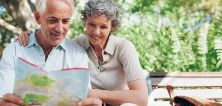 Ein Mann und eine Frau auf einer Parkbank beim Studieren einer Landkarte. (c) AdobeStock