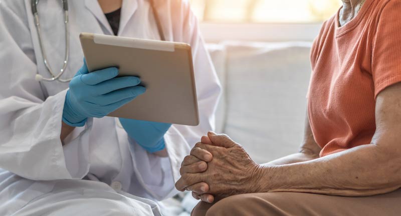 Die Hände einer alten Frau, die mit einer Ärztin spricht, die ihr auf einem Tablett einen Befund zeigt, Stichwort Parkinson.
(c) AdobeStock