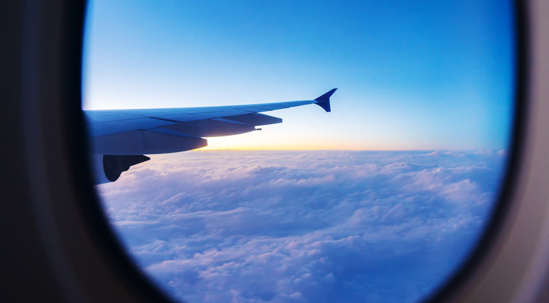 Der Blick aus dem Fenster eines Flugzeuges auf die darunter liegende Wolkendecke.
(c) AdobeStock