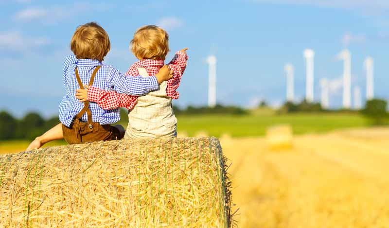 Green Care-Bauernhöfe: Projekt für mehr Lebensqualität im Alter 2 Zwei kleine Kinder auf einem Strohballen zeigen zum Horizont in Richtung Windräder, Stichwort Green Care.
(c) AdobeStock