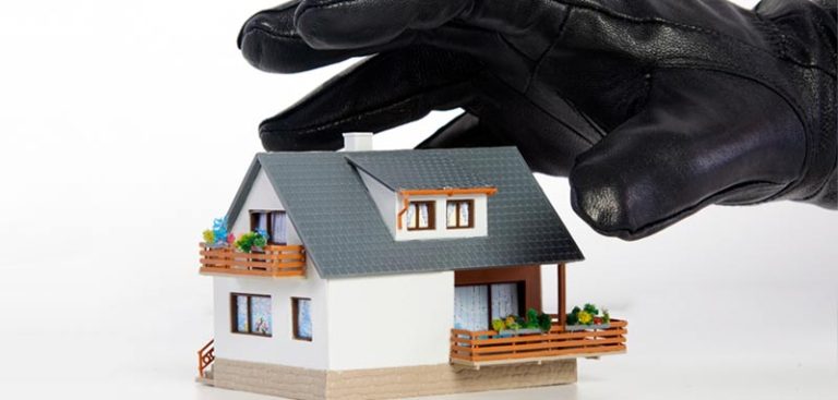 Illustration: eine Hand mit schwarzem Handschuh greift nach einem Haus. (c) AdobeStock
