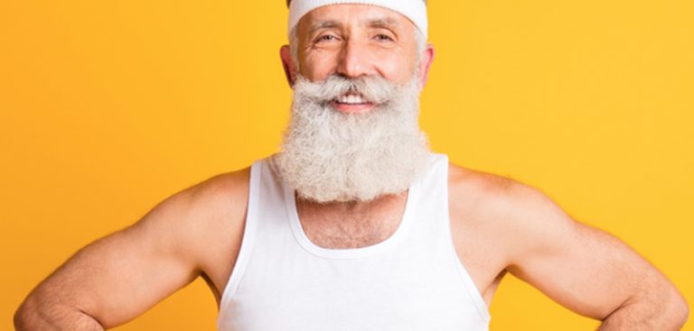 Ein älterer Mann mit weißem Vollbart und weißen Unterleiberl lacht in die Kamera. (c) AdobeStock