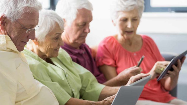 4 ältere Personen auf einer Couch mit Tablets. (c) AdobeStock