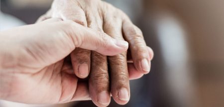 Die Hand einer Pflegerin, die die eines Patienten hält. (c) AdobeStock