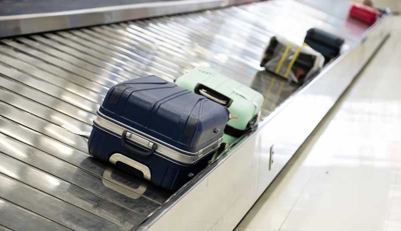 Koffer auf einem Förderband auf einem Flughafen, Stichwort Reisebeschwerden.
(c) AdobeStock