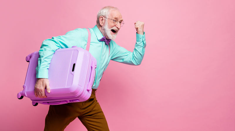Ein alter man mit einem Koffer unter dem Arm freut sich.
(c) AdobeStock