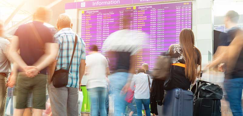 Menschen vor einer Anzeigetafel auf einem Flughafen. (c) AdobeStock