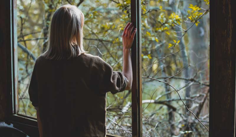 Psychisch erkrankte Menschen in Gesundheit und Rechten gefährdet 2 Eine Frau, die am Fenster steht und raus schaut.
(c) AdobeStock