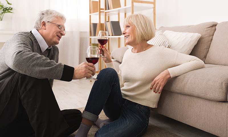 Studie: Diese 15 Faktoren halten Paare und Beziehungen zusammen 2 Ein älteres Paar sitzt auf dem Boden und prostet sich mit einem Glas Rotwein zu, Stichwort Paare.
(c) AdobeStock