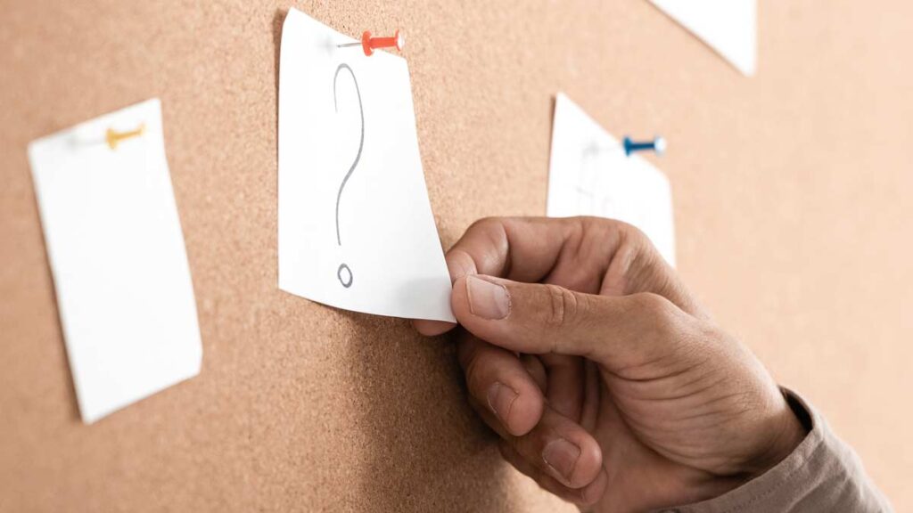 Demenz-Qualitätsregister tragen zu besseren Demenzversorgung bei Die Hand eines Mannes, der einen Zettel mit einem Fragezeichen auf einer Pinwand hält. (c) AdobeStock