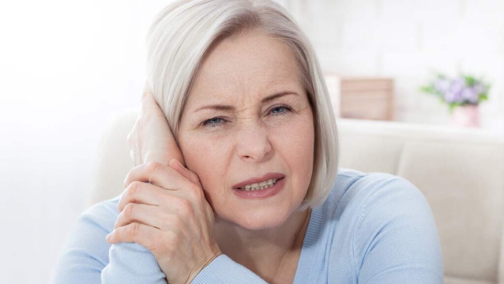 Eine Frau, die sich mit einer Hand ihr schmerzendes Ohr hält. (c) AdobeStock