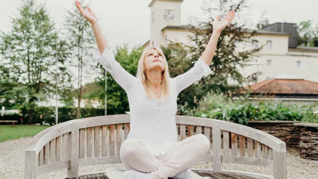 Eine Frau beim Yoga auf einer Bank vor einem Kloster, Stichwort Klösterreich. (c) Curhaus Marienschwestern GmbH/ Christina Baireder