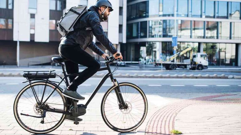 Ein Mann auf einem Fahrrad auf einem Platz in einer Stadt. (c) ergotec/ Aktion Gesunder Rücken
