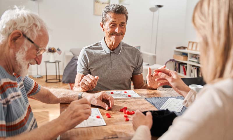 Gesundes Altern vor dem Hintergrund einer alternden Gesellschaft 2 Drei ältere Personen an einem Tisch bei einem Spiel.
(c) AdobeStock