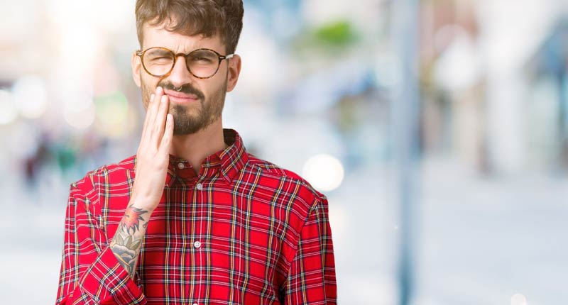 #Mundgesundheit: Gesundes Zahnfleisch steht dir gut! Schütze es! 1 Ein junger Mann, der sich wegen Zahnschmerzen auf seinen Unterkiefer greift, Stichwort Mundgesundheit.
(c) AdobeStock