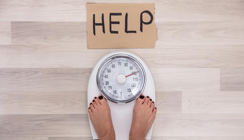 Aktuelle Studie zeigt: Adipositas erhöht Risiko für psychische Störungen 2 Die Füße einer Frau auf einer Körperwaage, davor ein Schild, auf dem "Help" steht.
(c) AdobeStock