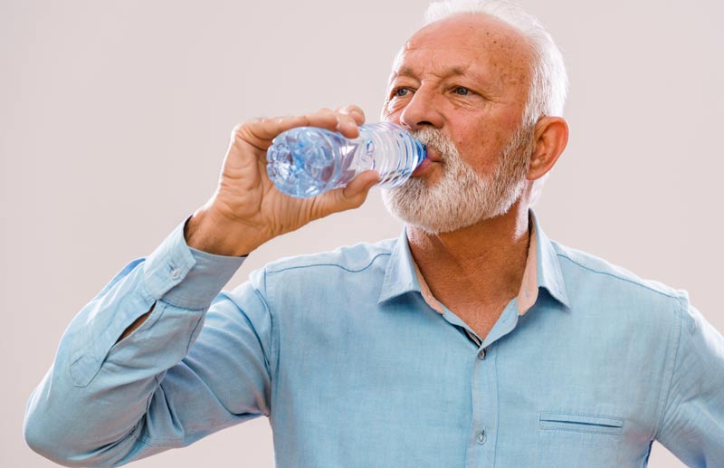 Ein älterer Mann trinkt aus einer Wasserflasche.
(c) AdobeStock