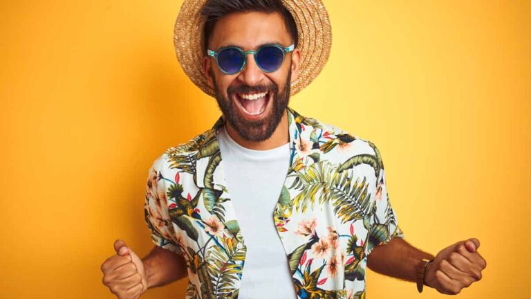 Ein Mann mit Sonnenhut, Sonnenbrille und Safari-Hemd freut sich. (c) AdobeStock