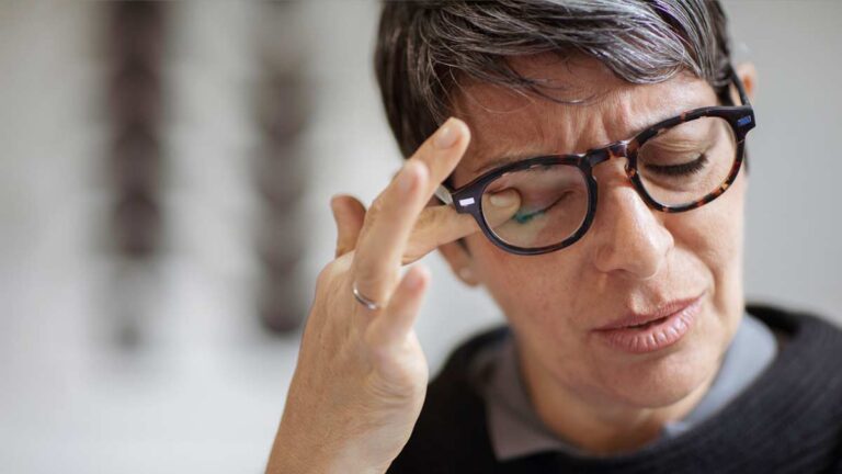 Der Kopf einer Frau mit Brille, die sich mit dem Finger ihre müden Augen reibt. (c) AdobeStock