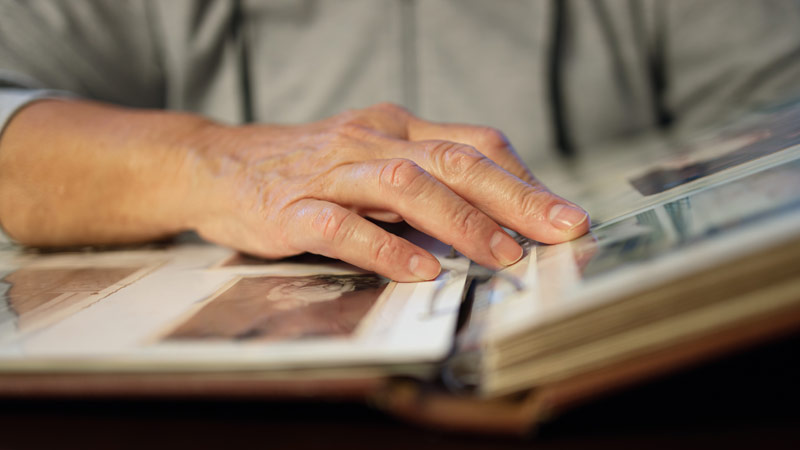 Die Hand einer alten Frau, die in einem Fotoalbum blättert.
(c) AdobeStock
