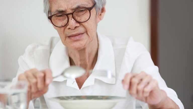 Ein älterer Mann mit Brille mit Löffel und Gabel in den Händen vor einem Teller. (c) AdobeStock