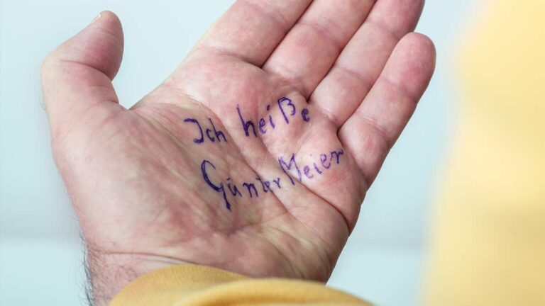 Die Handfläche eines Mannes, auf der geschrieben steht: "Ich heiße Günter Meier".