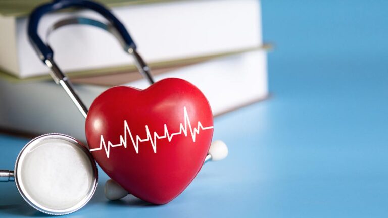Ein rotes Herz mit Herzschlaglinien vor einem Stethoskop. (c) AdobeStock