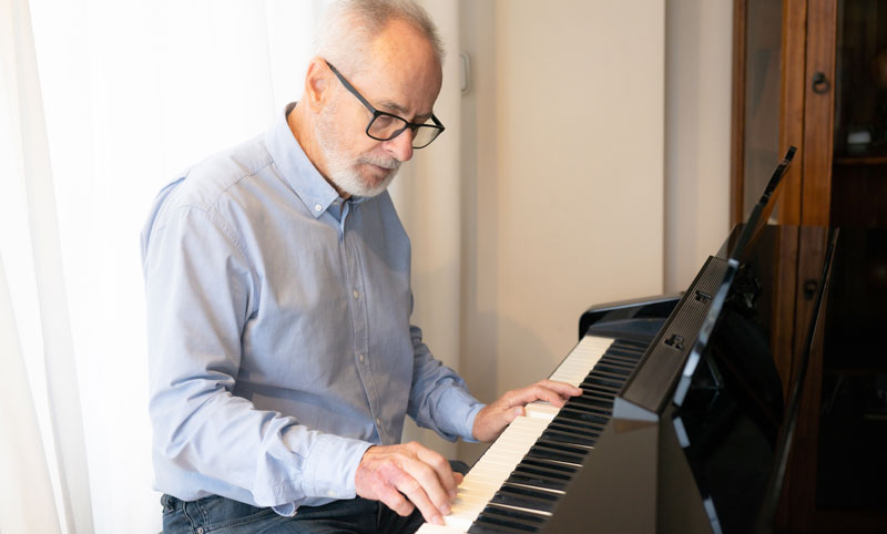 Gitarre, Klavier, Flöte & Co. – für ein Musikinstrument ist man nie zu alt 1 Ein älterer Mann mit Brille beim Klavierspielen, Stichwort Musikinstrument.
(c) AdobeStock