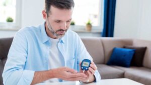 Diabetes-Risiko erkennen und handeln – je früher, desto besser! Ein Mann sitzt an einem Tisch und misst seinen Blutzuckerwert. (c) AdobeStock