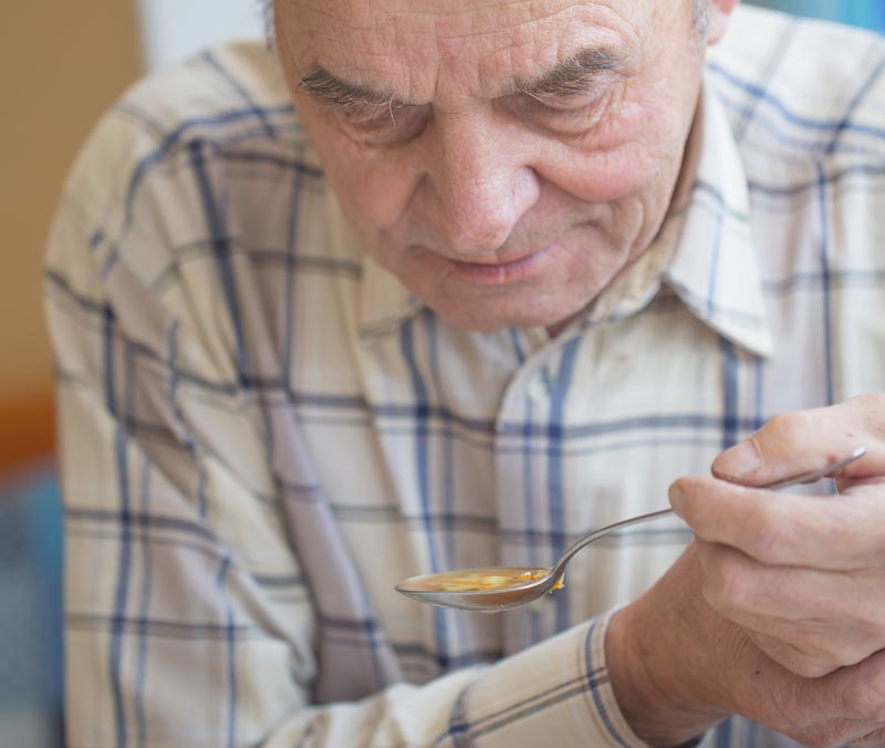 Bewegungsstörungen haben kein Alter, aber viele Erscheinungsformen 2 Ein Mann, der mit einem Löffel Suppe isst und mit seiner anderen Hand diese halten muss, Stichwort Bewegungsstörung.
(c) AdobeStock