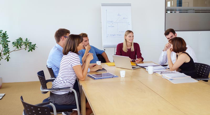 Besprechung in einem Meetingraum mit sechs Teilnehmer•innen, Stichwort Corona-Studie.
(c) AdobeStock