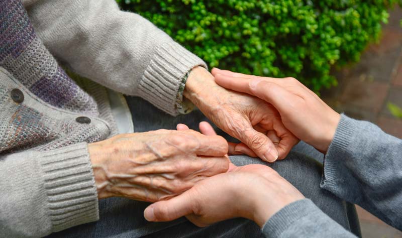 Die Hände eines alten Menschen, die von denen einer Pflegerin gehalten werden.
(c) AdobeStock