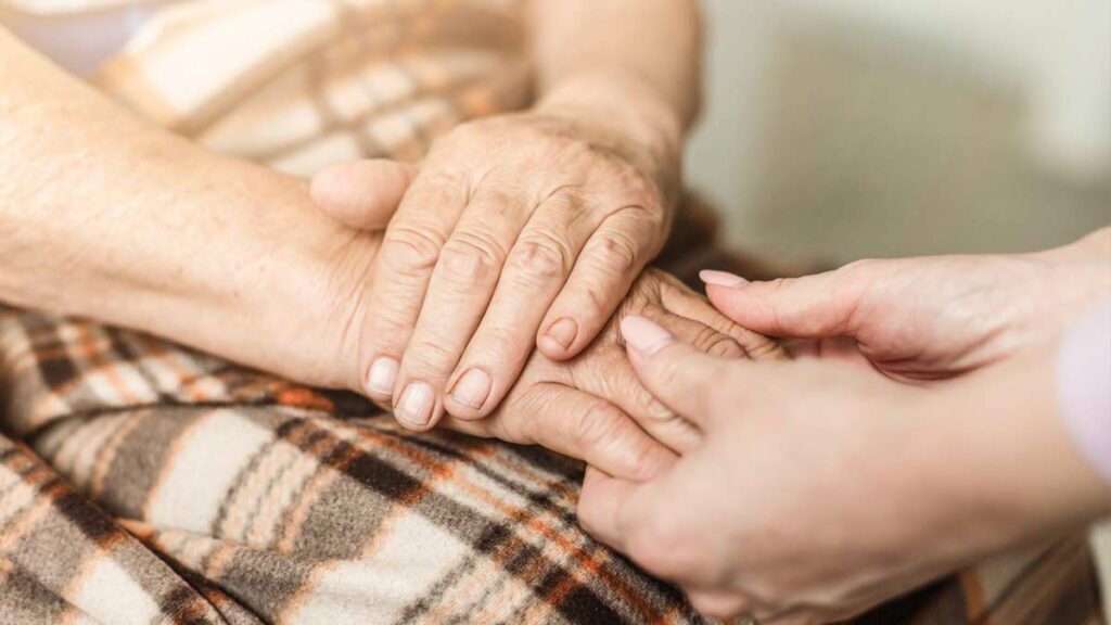 Die Hände einer alten Frau, die von einer jungen Frau gehalten werden. (c) AdobeStock