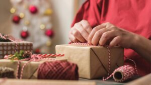 VKI-Tipps: Was tun, wenn das Weihnachtsgeschenk nicht passt? Die Hände einer älteren Frau, die ein Geschenk verpackt. (c) AdobeStock