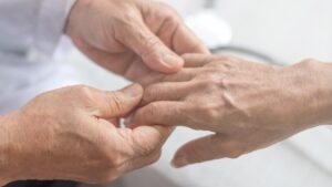 Die Hände einer Pflegerin, die die Hand einer alten Person hält. (c) AdobeStock