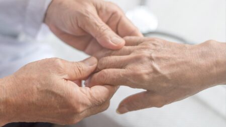 Die Hände einer Pflegerin, die die Hand einer alten Person hält. (c) AdobeStock